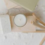 Candle surrounded by natural elements like soap and botanicals, symbolizing chronic illness self-care