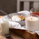 September candle on a breakfast tray with jam and linen on a wooden table.