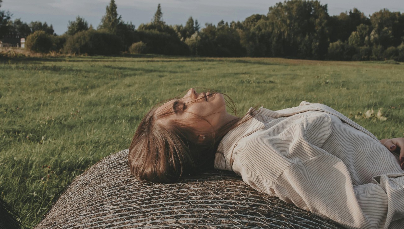 woman resting outdoors in sunlight representing peace, recovery, and gentle living with chronic illness