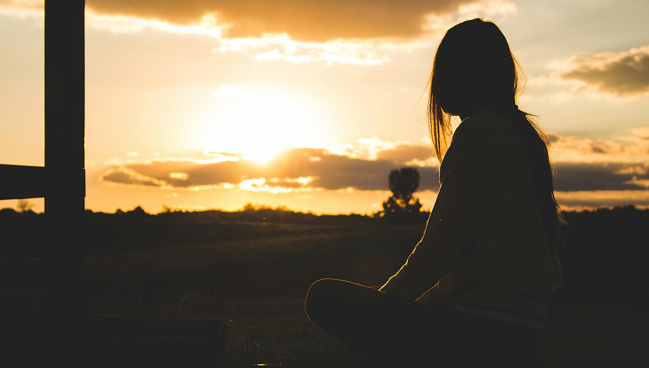 a girl relaxing looking at a sunrise